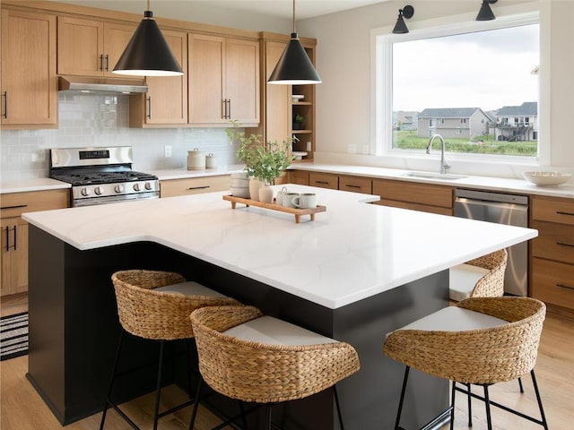 kitchen featuring a breakfast bar, ventilation hood, stainless steel appliances, sink, and light hardwood / wood-style flooring