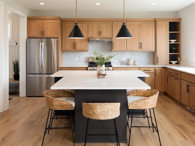 kitchen featuring stainless steel fridge, stove, pendant lighting, and light wood-type flooring