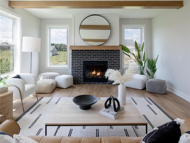 living room featuring a tile fireplace, light hardwood / wood-style flooring, and beamed ceiling