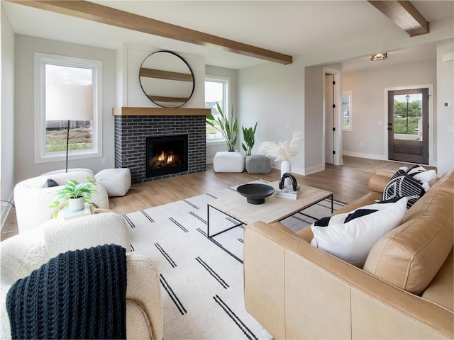 living room featuring beam ceiling, light wood-type flooring, and a healthy amount of sunlight