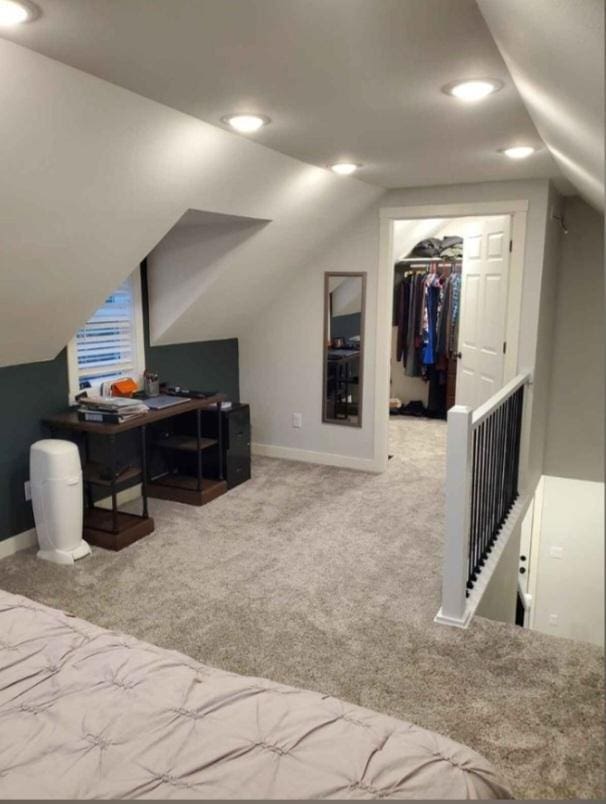 bedroom with a walk in closet, carpet floors, a closet, and lofted ceiling