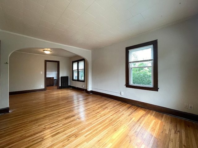 empty room with wood-type flooring and crown molding