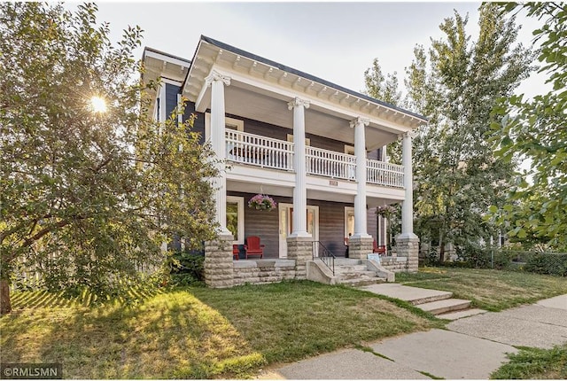 view of front of property featuring a porch, a balcony, and a front yard