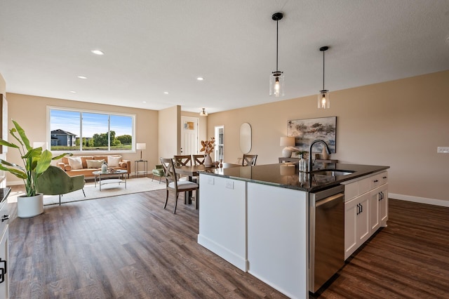 kitchen with white cabinets, sink, hanging light fixtures, stainless steel dishwasher, and an island with sink