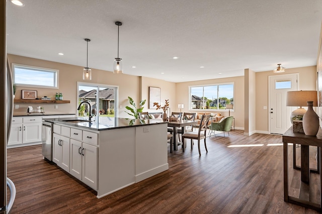 kitchen with white cabinets, sink, dark hardwood / wood-style floors, an island with sink, and decorative light fixtures