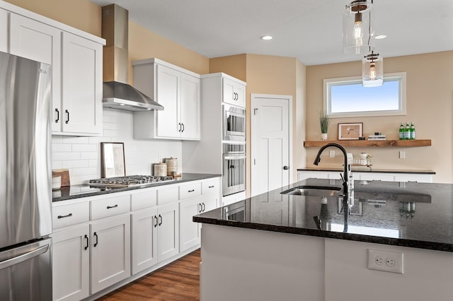 kitchen featuring white cabinets, stainless steel appliances, wall chimney exhaust hood, and sink