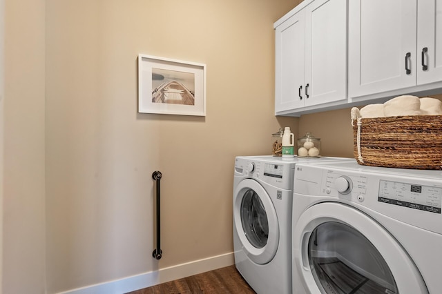 clothes washing area featuring dark hardwood / wood-style flooring, washer and clothes dryer, and cabinets