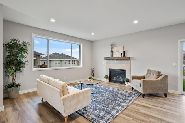 living room with a tiled fireplace and hardwood / wood-style floors