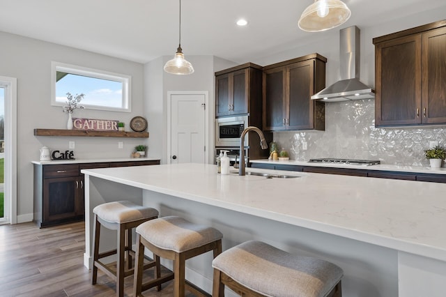 1242 Willowbrook Cir, Delano, MN 55328 - kitchen featuring wall chimney exhaust hood, appliances with stainless steel finishes, backsplash, dark brown cabinetry, and a kitchen breakfast bar