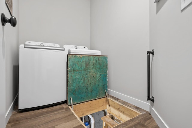 clothes washing area featuring washing machine and dryer and hardwood / wood-style flooring