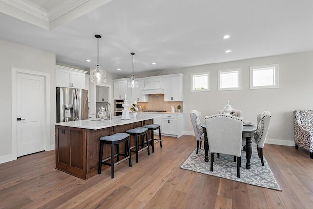 dining area featuring light hardwood / wood-style floors, ornamental molding, and sink