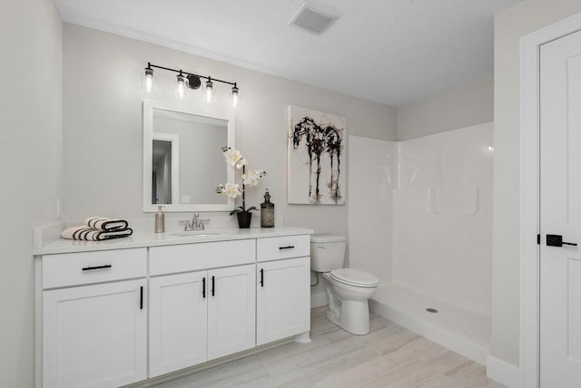 bathroom featuring hardwood / wood-style flooring, toilet, a shower, and vanity