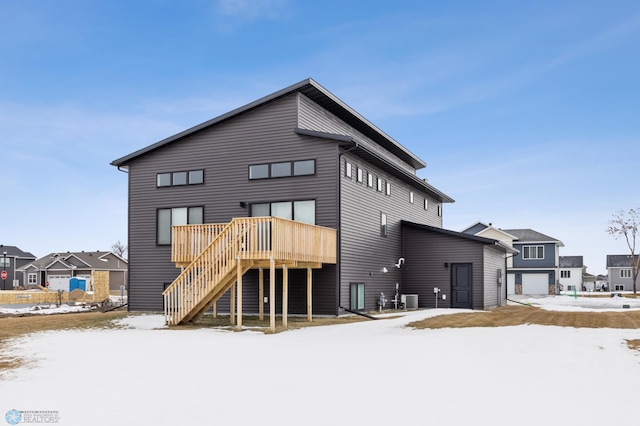 snow covered property featuring a garage, cooling unit, and a wooden deck