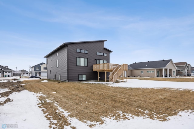 snow covered back of property featuring a yard and a wooden deck