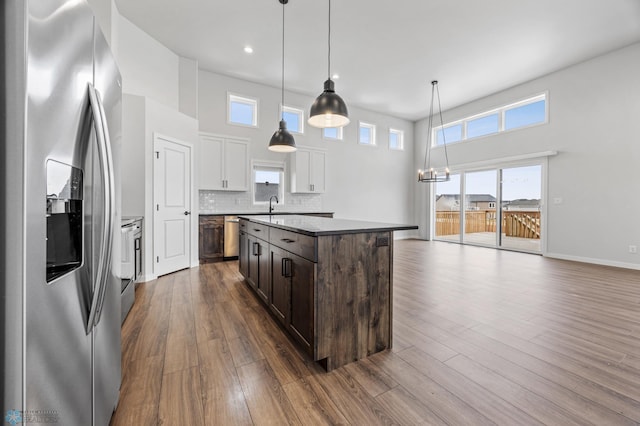 kitchen featuring dark brown cabinetry, stainless steel appliances, decorative light fixtures, a center island, and white cabinetry