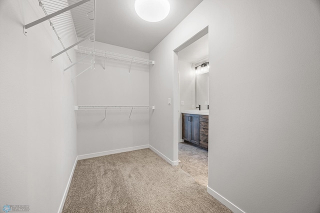 walk in closet with light carpet and sink