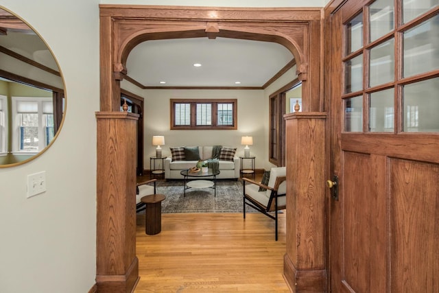 corridor with ornamental molding and light hardwood / wood-style floors