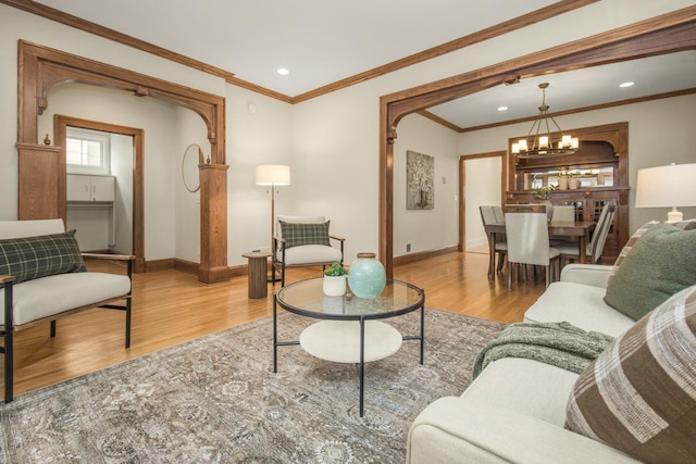 living room featuring crown molding, light hardwood / wood-style flooring, and a notable chandelier