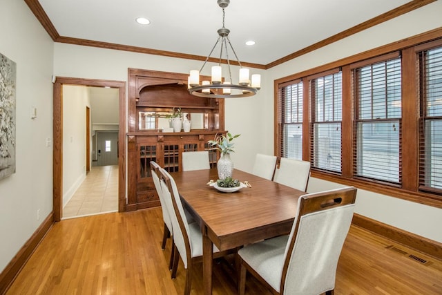 dining space featuring crown molding, a chandelier, and light hardwood / wood-style flooring