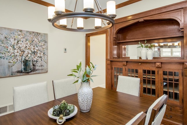 dining space with crown molding and a notable chandelier