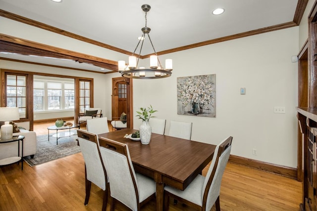 dining room with a fireplace, light hardwood / wood-style flooring, ornamental molding, and a chandelier