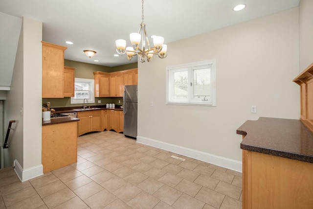 kitchen with a wealth of natural light, sink, pendant lighting, and stainless steel fridge