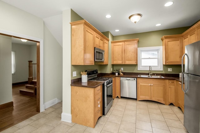 kitchen with dark stone countertops, sink, light tile patterned floors, and appliances with stainless steel finishes