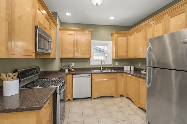 kitchen featuring appliances with stainless steel finishes, sink, light tile patterned floors, and dark stone counters