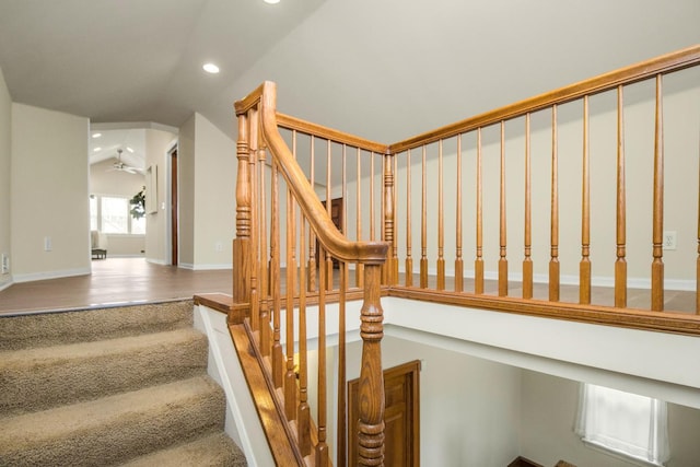 stairs featuring ceiling fan, lofted ceiling, and carpet floors