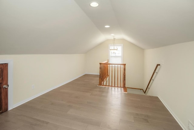 additional living space with lofted ceiling and light hardwood / wood-style flooring