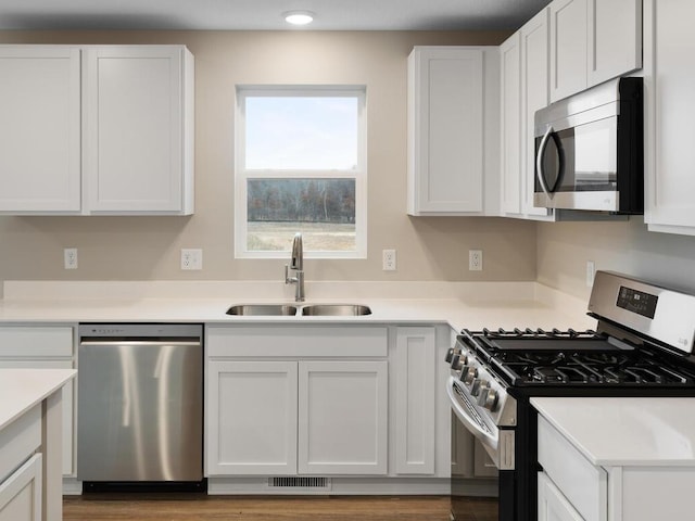 kitchen with appliances with stainless steel finishes, sink, and white cabinetry