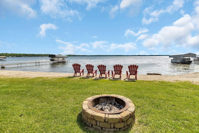 view of dock with a yard, a water view, and a fire pit