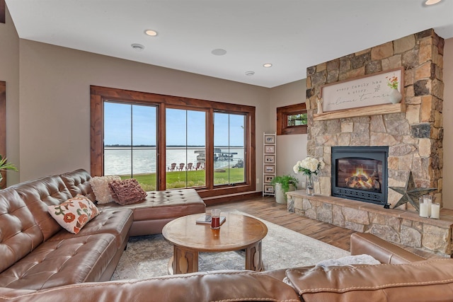 living room with a fireplace, light wood-type flooring, and a water view