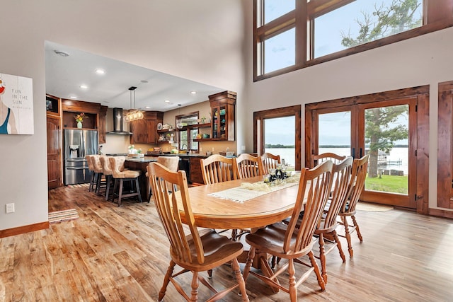 dining space with light wood-type flooring, sink, and a towering ceiling