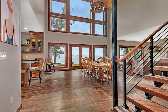 dining room with a high ceiling, a water view, plenty of natural light, and hardwood / wood-style floors