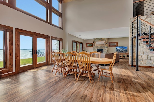 dining area with a towering ceiling, a fireplace, a water view, and plenty of natural light