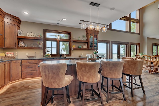 kitchen with pendant lighting, light hardwood / wood-style floors, a kitchen bar, and sink