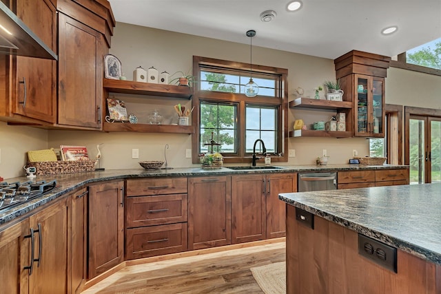 kitchen with stainless steel dishwasher, exhaust hood, light hardwood / wood-style flooring, dark stone countertops, and hanging light fixtures