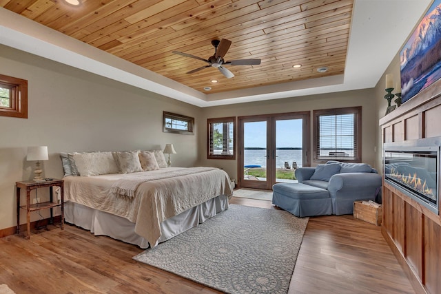 bedroom with access to outside, a raised ceiling, a water view, ceiling fan, and wood ceiling