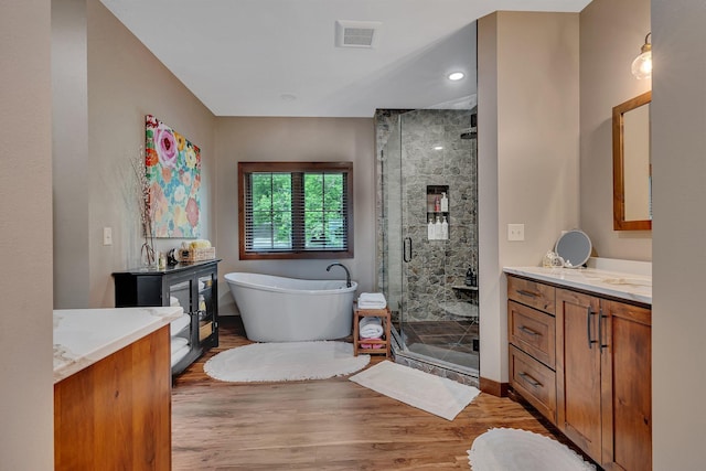 bathroom featuring hardwood / wood-style flooring, vanity, and plus walk in shower