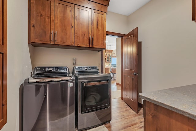 laundry area with cabinets, light wood-type flooring, and washing machine and dryer