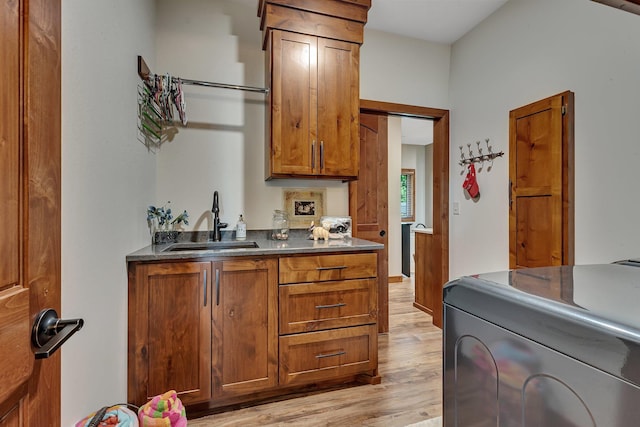 kitchen with washer / dryer, sink, and light hardwood / wood-style flooring