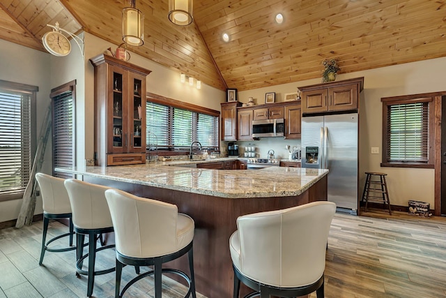 kitchen featuring light stone counters, stainless steel appliances, high vaulted ceiling, and wood ceiling