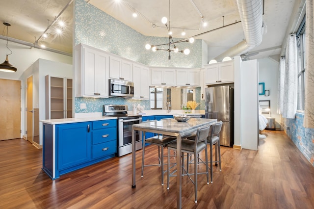 kitchen featuring blue cabinetry, stainless steel appliances, rail lighting, light countertops, and white cabinetry