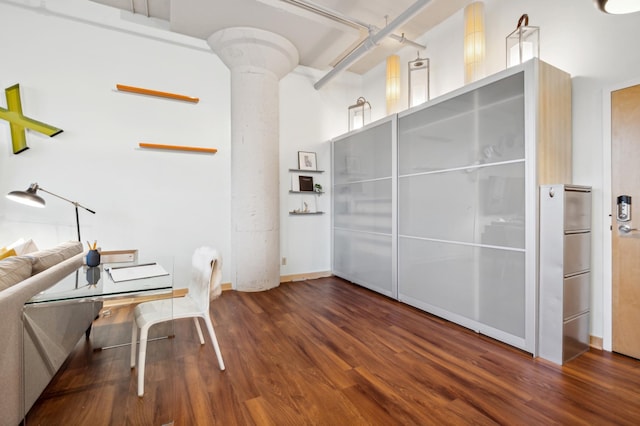 office area featuring wood finished floors, decorative columns, and baseboards