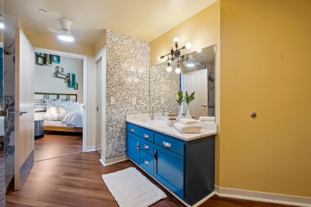 ensuite bathroom featuring wood finished floors, vanity, and baseboards