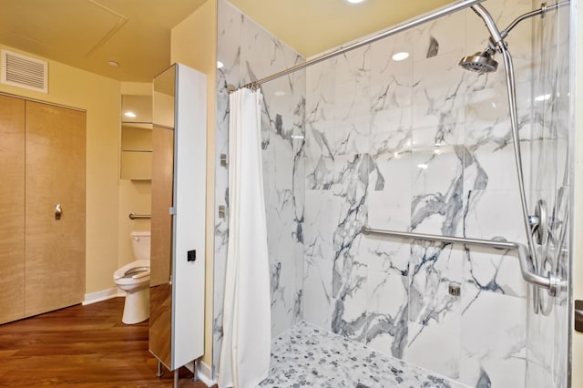 bathroom featuring a marble finish shower, wood finished floors, and toilet