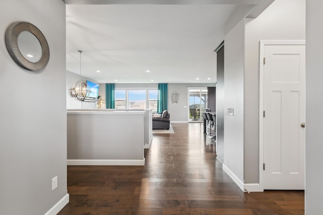 hallway featuring an inviting chandelier and dark wood-type flooring