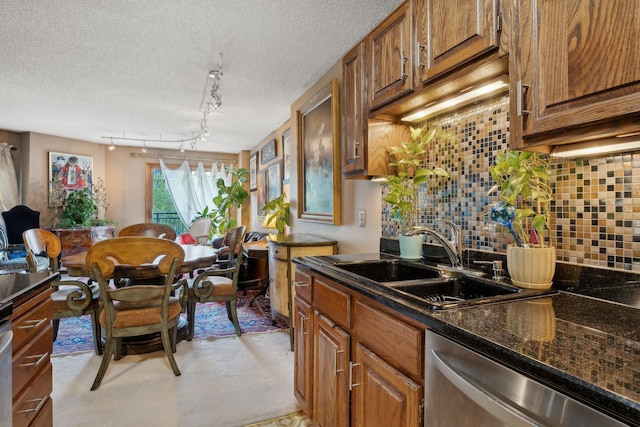 kitchen featuring backsplash, stainless steel dishwasher, dark stone counters, a textured ceiling, and sink