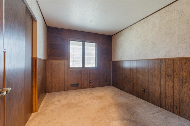 carpeted spare room with wood walls